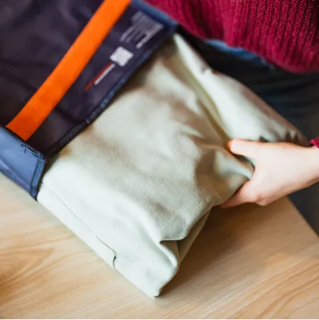 Eine Person entnimmt Kleidung aus einer geöffneten Boomerang Mehrwegversandtasche